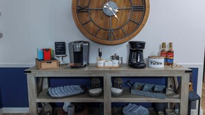A wooden coffee table with a clock, coffee maker, and bottles. - Private, Updated Baileys Harbor Home: The Roost (Baileys Harbor)