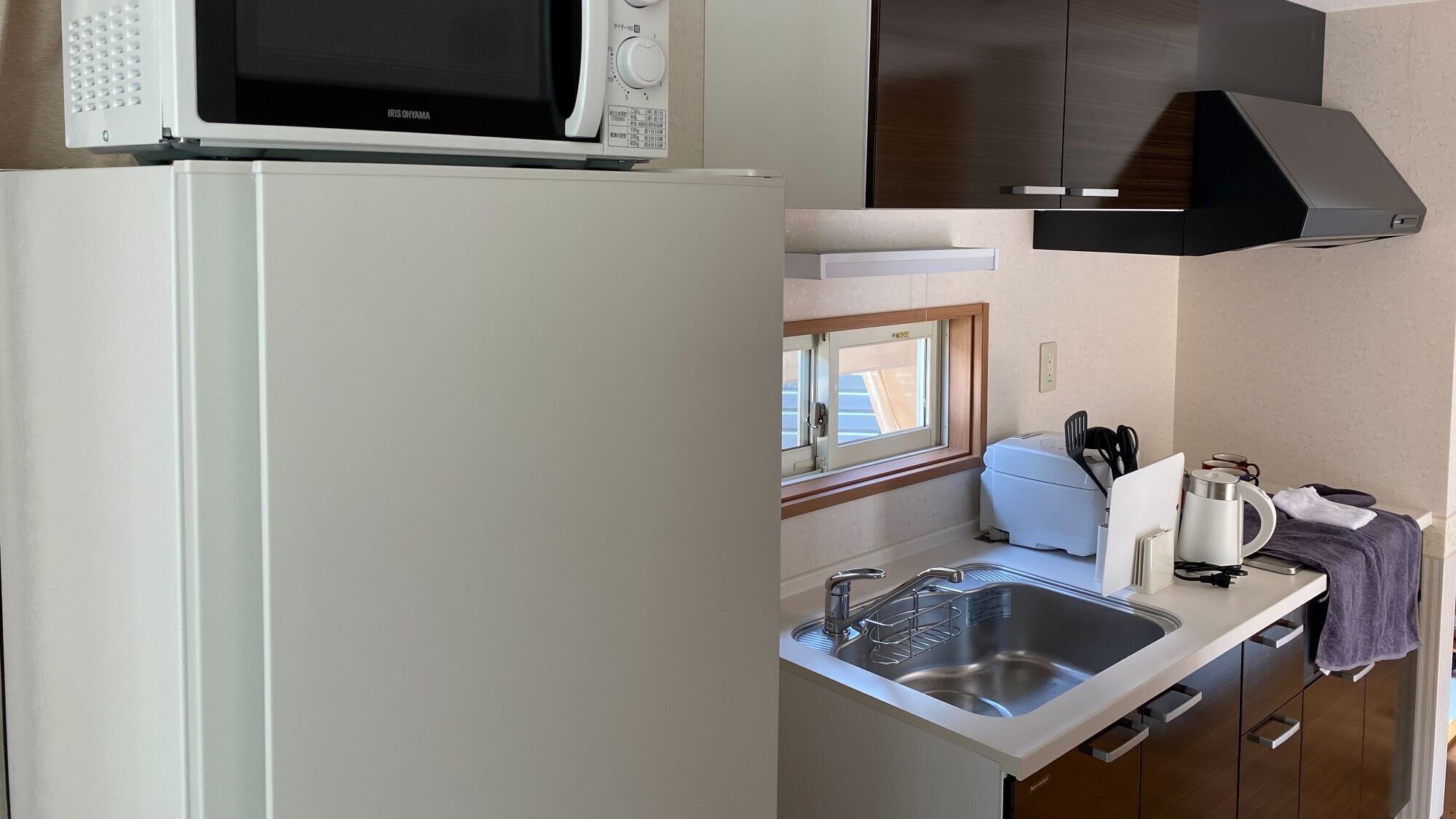 A compact kitchenette with a microwave, sink, and stove.