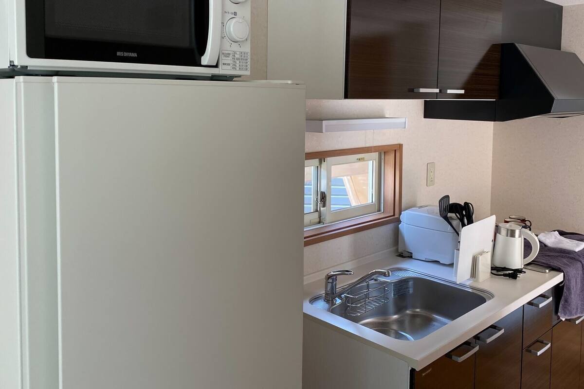 Una kitchenette compacta con microondas, pileta y cocina.