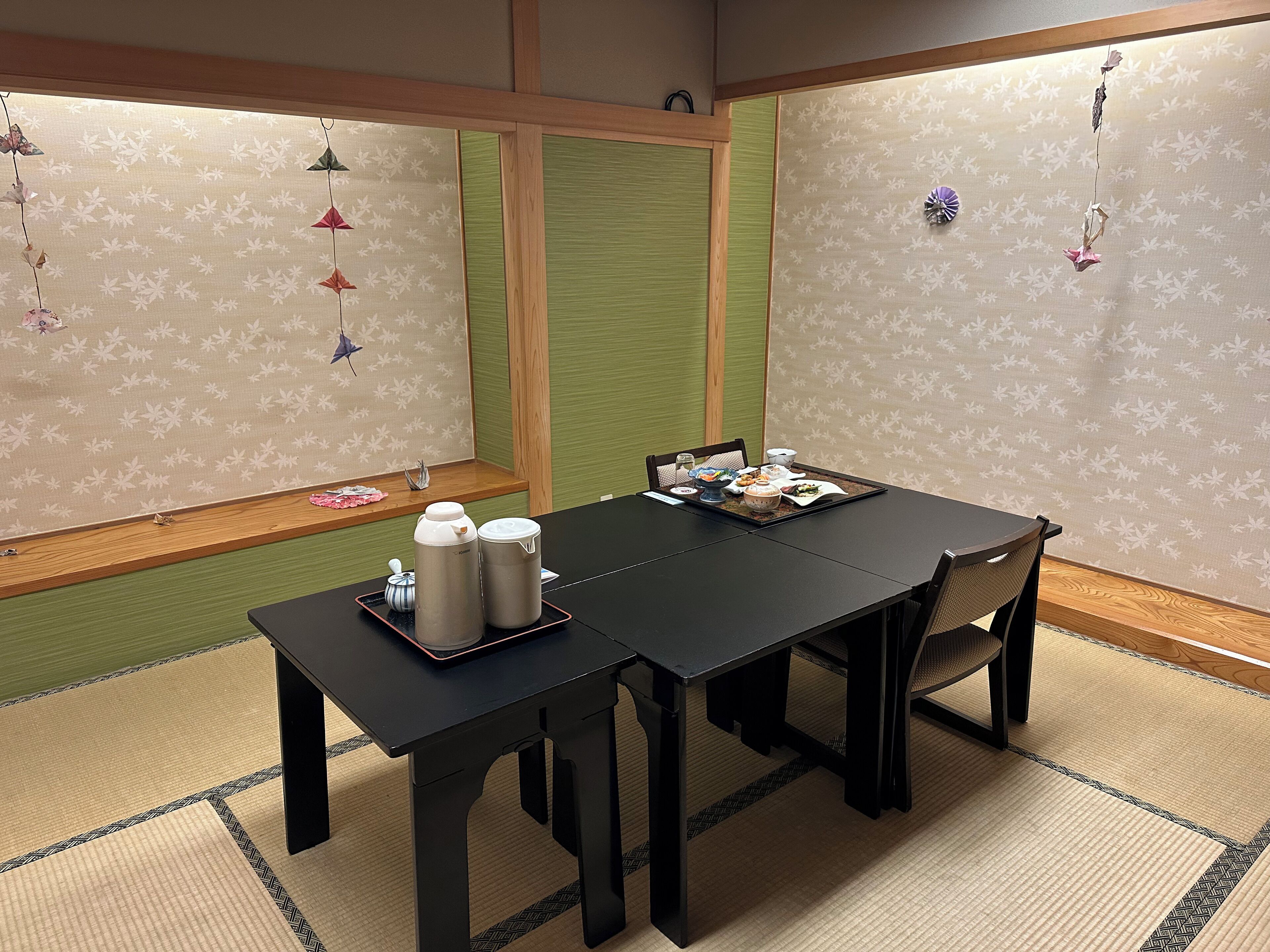 Una habitación japonesa tradicional con suelo de tatami, una mesa baja con un juego de té y una puerta corredera.