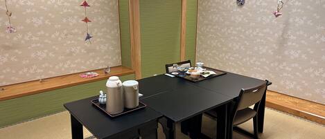 Una habitación japonesa tradicional con suelo de tatami, una mesa baja con un juego de té y una puerta corredera.