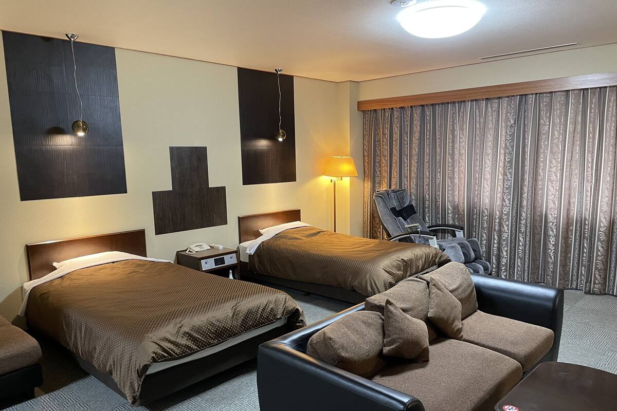 Habitación de hotel con dos camas, un sofá, un escritorio y una lámpara.