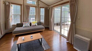 Una habitación acogedora con un sofá, una mesita y un ventanal grande.