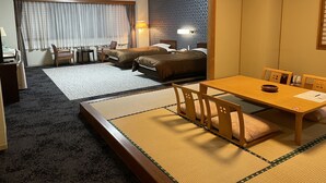 Una habitación tradicional japonesa con esteras de tatami, una mesa baja con un cuenco y una cama con un muro estampado de fondo.