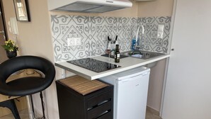 A compact kitchen with a built-in dishwasher, a small bar stool, and a decorative backsplash. - Cozy apartment in heart Athens near metro Fix 100m (Athina)