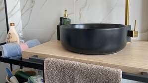 A bathroom with a black vessel sink, a gold faucet, and toiletries on the counter. - Cozy apartment in heart Athens near metro Fix 100m (Athina)