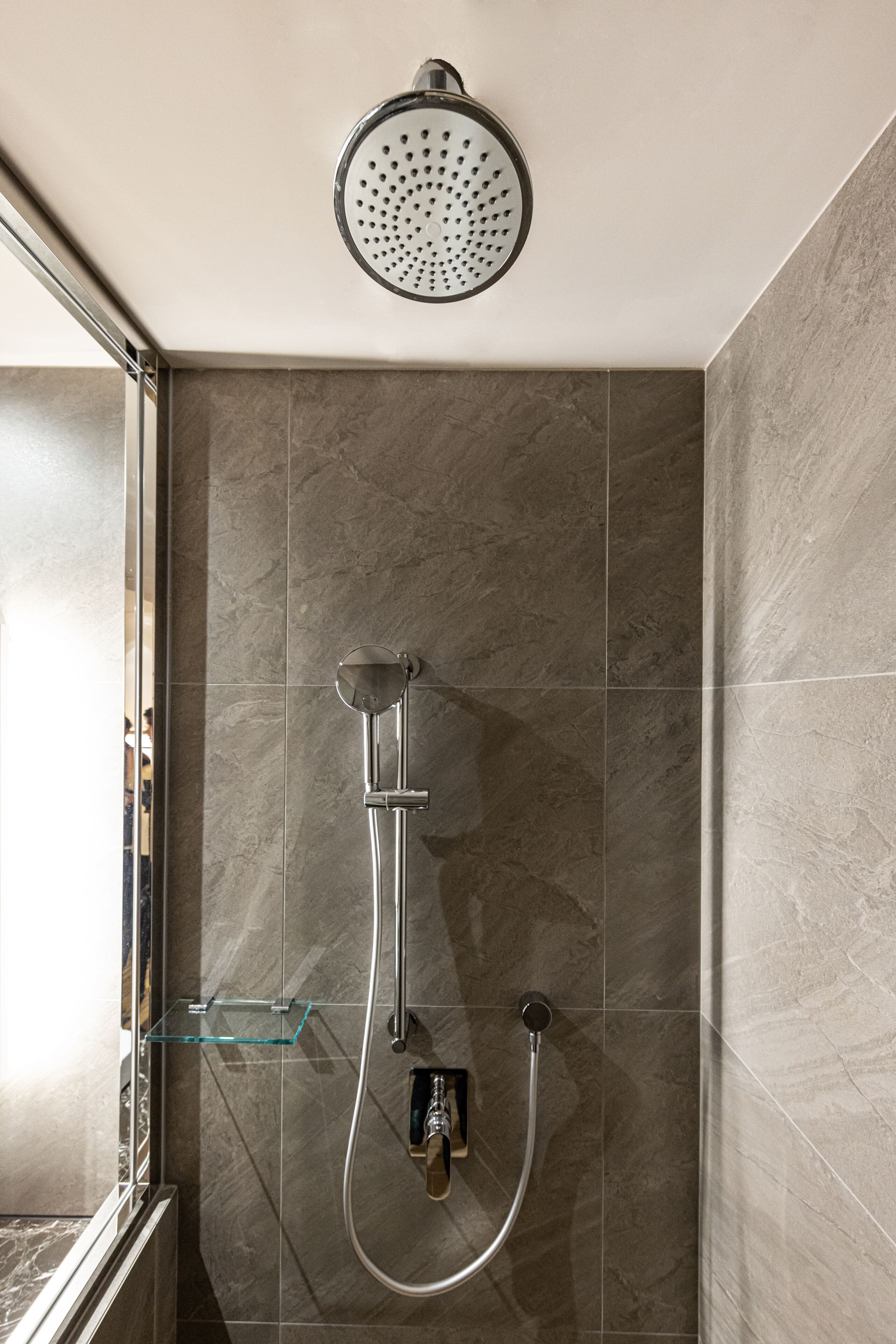 A modern shower with a handheld showerhead and a wall-mounted faucet.