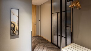 A hallway with a wooden floor, a framed artwork on the wall, and a wooden bench.