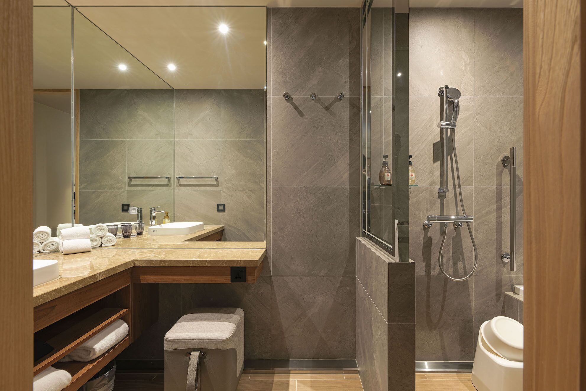 A modern bathroom with a glass-enclosed shower, a vanity with a sink, and a toilet.
