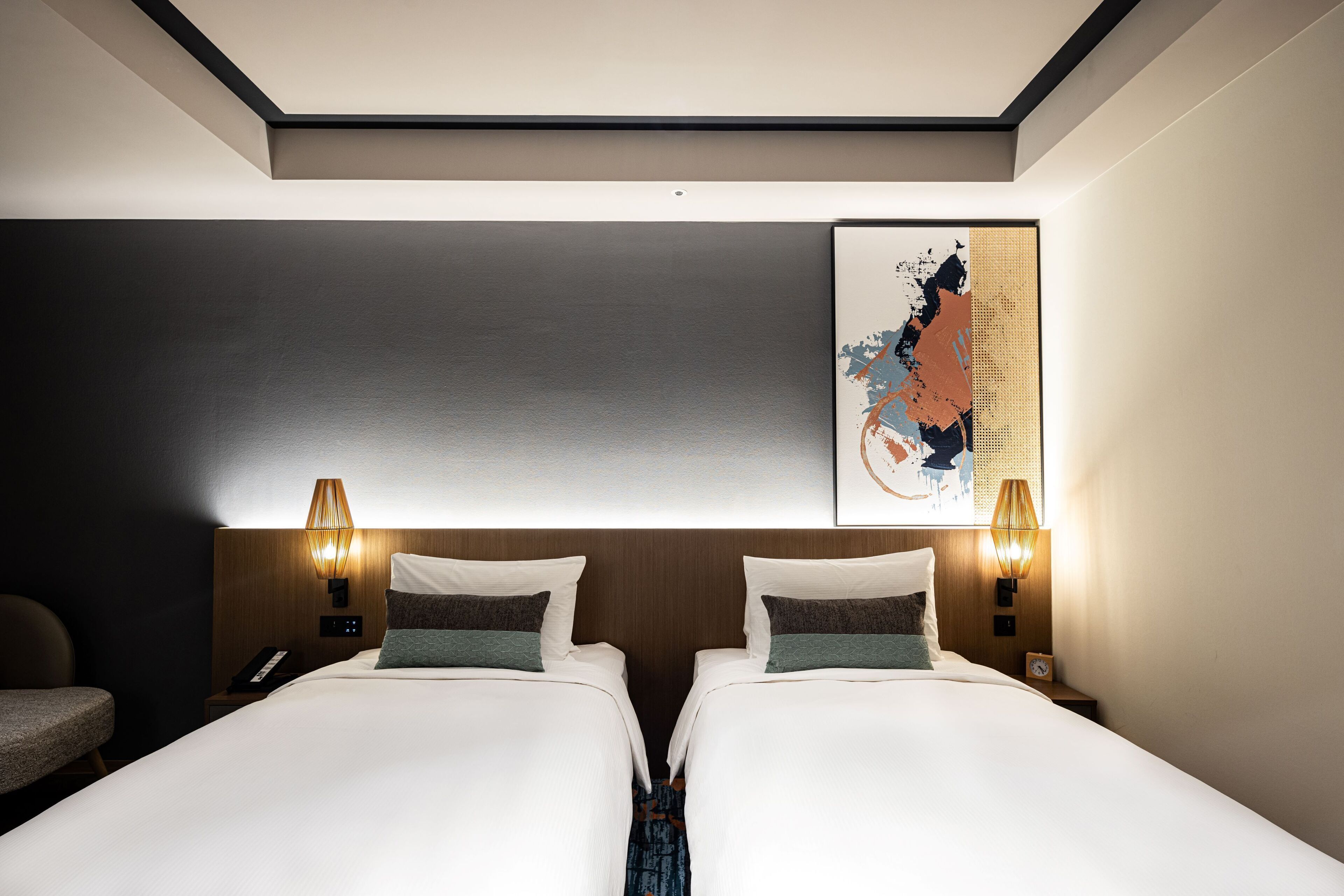 A hotel room with two beds, a large abstract painting on the wall, and two bedside lamps.