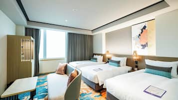 A hotel room with three beds, a desk, and a chair.