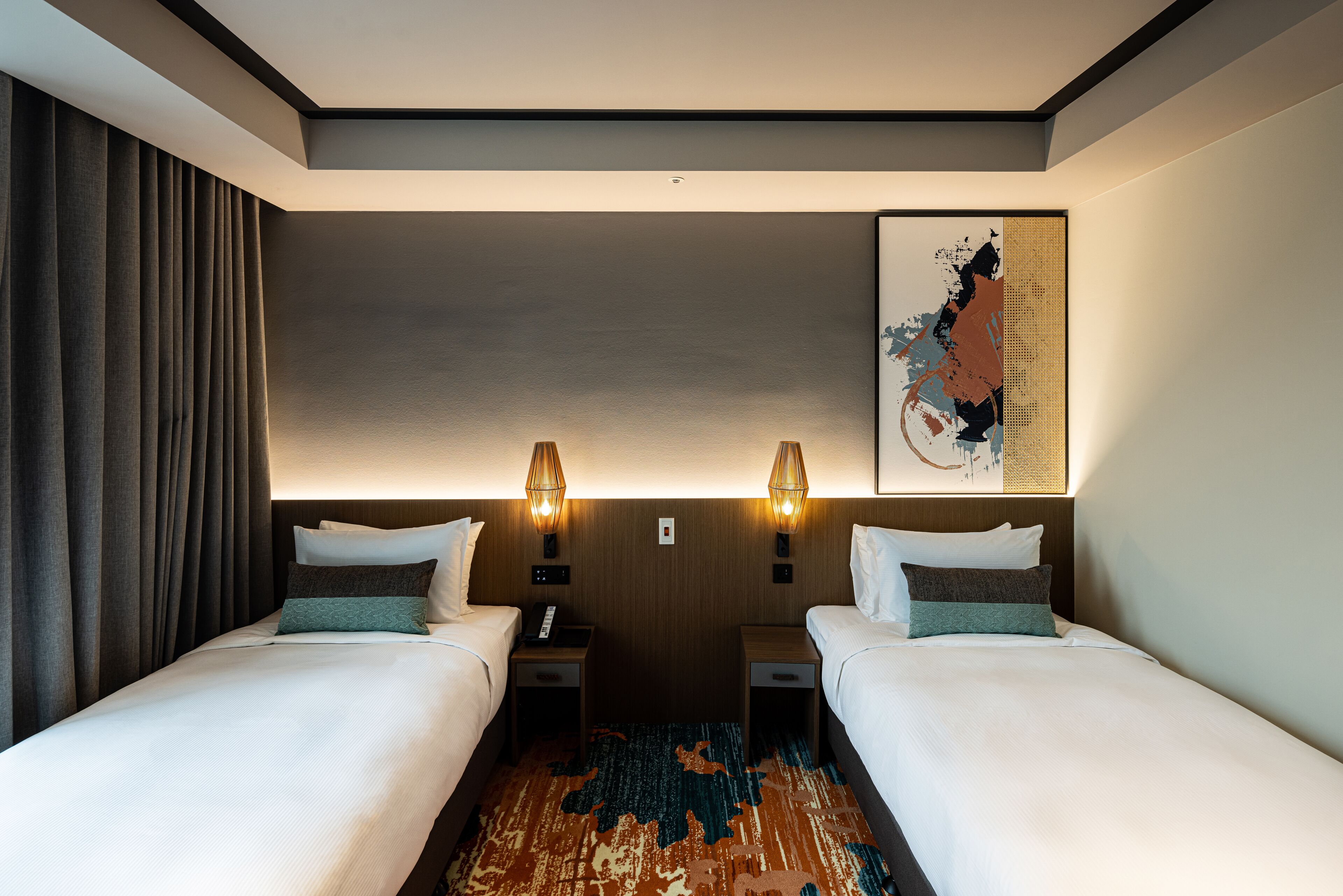 A hotel room with two beds, a large abstract artwork on the wall, and a patterned rug on the floor.