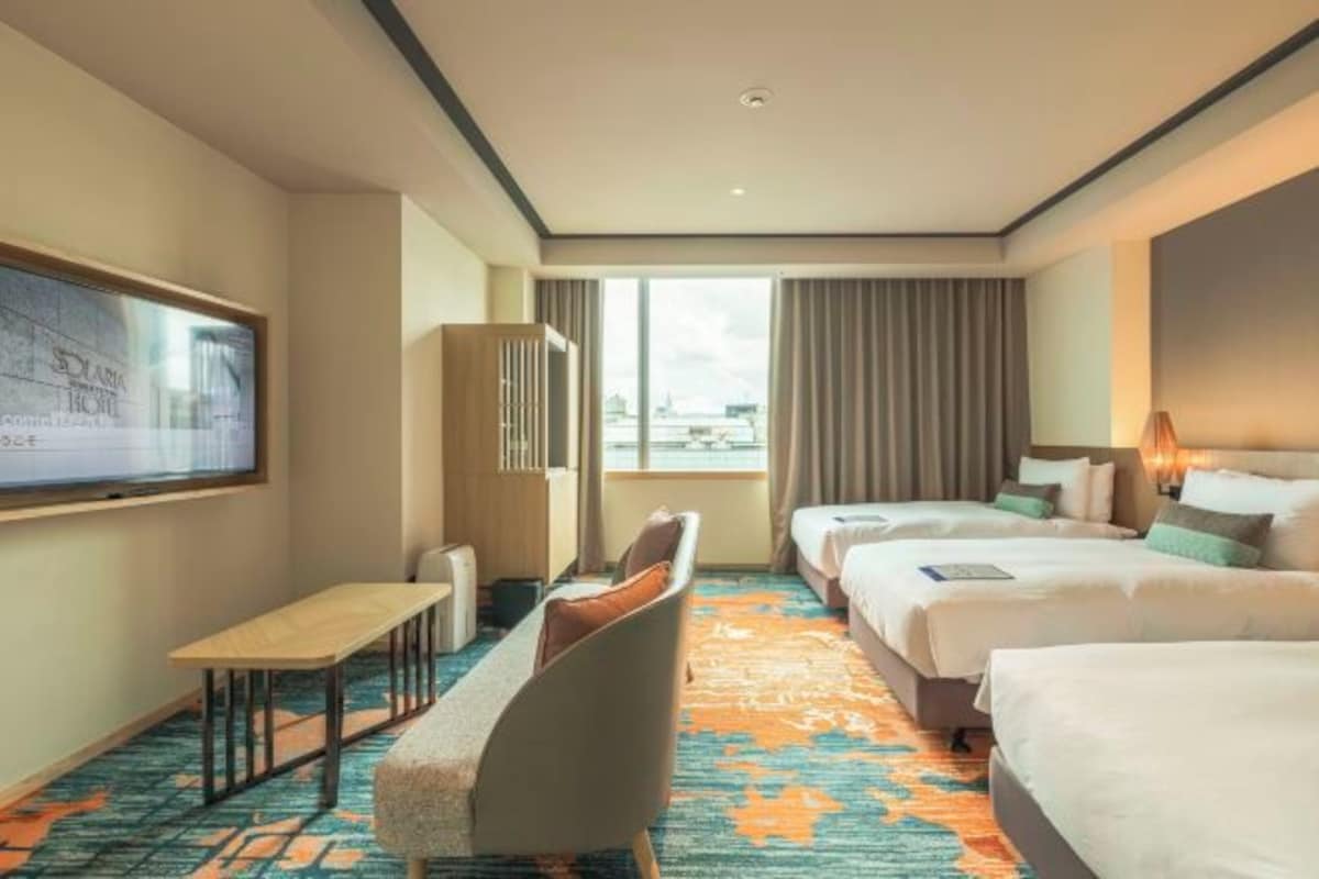 Een hotelkamer met een bed, een bureau, een stoel en een groot raam.