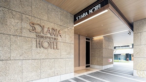 The entrance to Solaria Nishitetsu Hotel with a modern design, featuring a stone facade and a wooden ceiling.