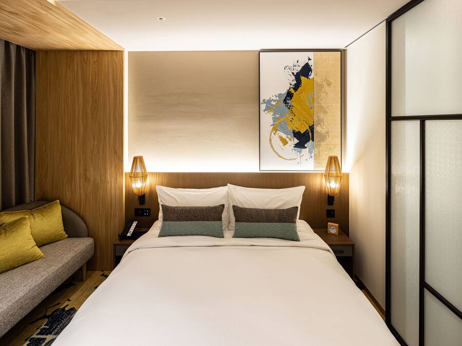 Una habitación de hotel con una cama, un sofá y una obra de arte colgada en la pared.