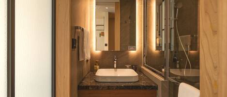 A modern bathroom with a marble sink, a large mirror, and a glass shower enclosure.
