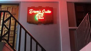 Eine Treppe mit einem Neonzeichen für 'Dave's Suite', das die Öffnungszeiten anzeigt.