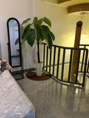 A room with a bed, a potted plant, a mirror, and a staircase railing. - Daves Suite (Sipocot)