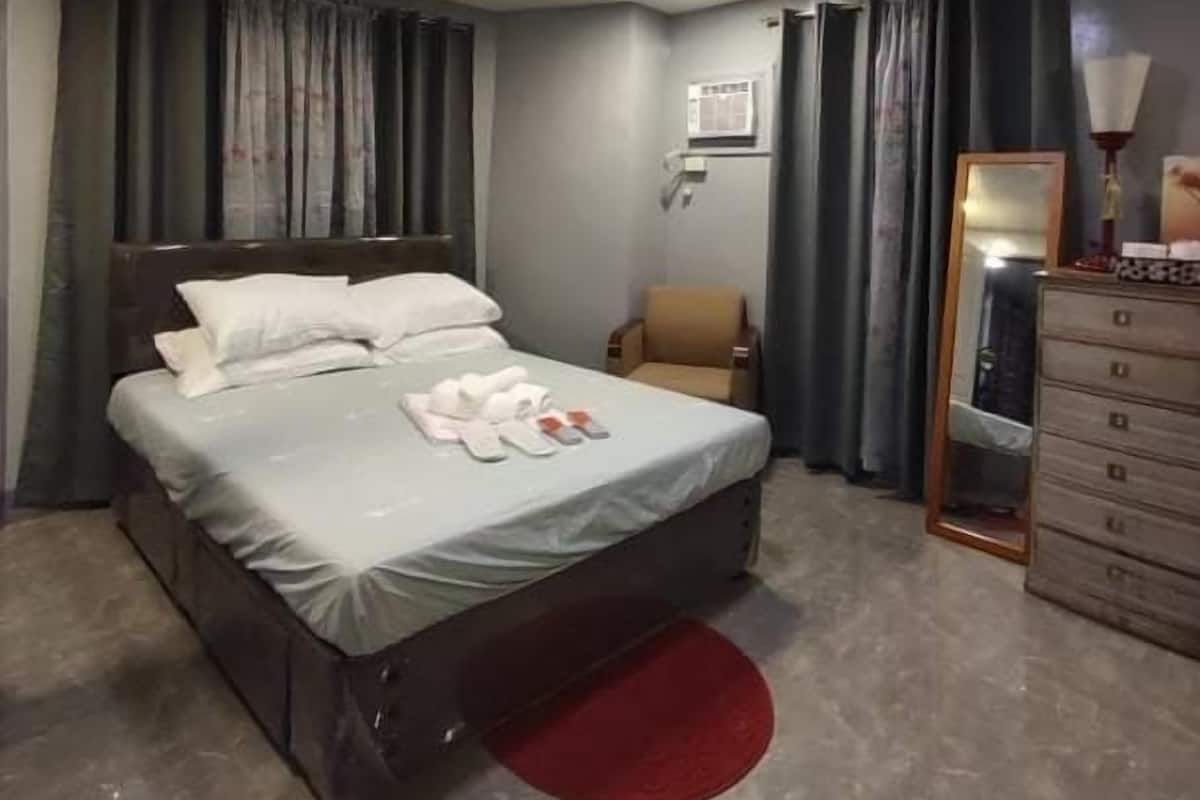 Un dormitorio con una cama, una silla, un tocador y un espejo.