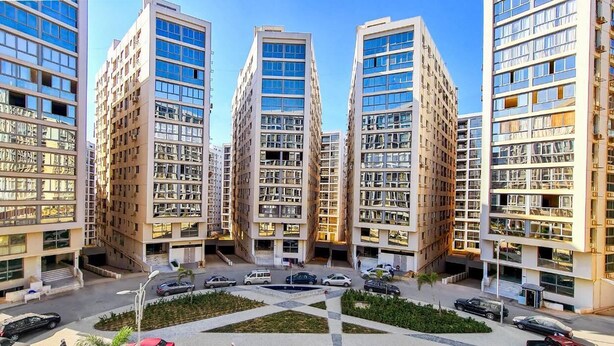 Un complesso residenziale moderno con diversi palazzi di grandi dimensioni, un cortile centrale e un'area di parcheggio.