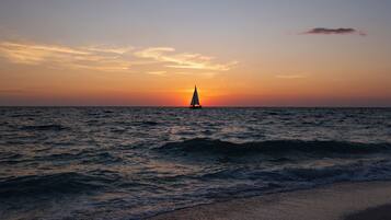 A sunset over the ocean with a sailboat.