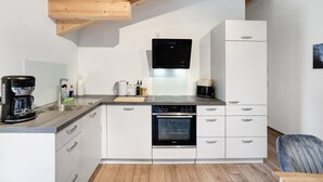 Uma cozinha moderna com armários brancos, forno embutido, lava-louças e máquina de café.