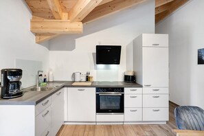 A modern kitchen with white cabinets, a built-in oven, a dishwasher, and a coffee maker.