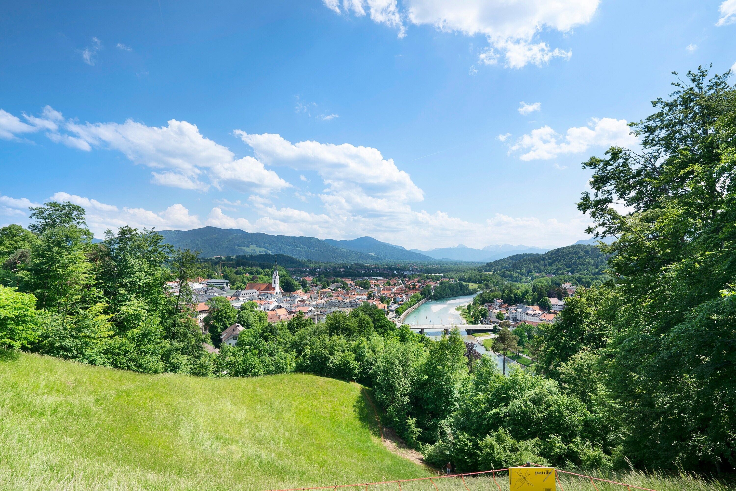 Une ville traversée par une rivière, entourée de verdure et de collines.