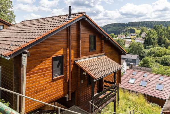 Une cabane en bois avec un toit en pente, un balcon et une vue sur un village.