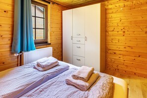 Une pièce en bois avec un lit, une armoire et une fenêtre avec des rideaux.