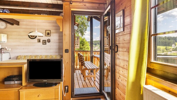 A wooden cabin interior with a television, wooden furniture, and a view of the outdoors. - Holiday Home 'Sommerberg' with Mountain View, Balcony and Wi-Fi (Unterkirnach)