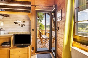 A wooden cabin interior with a television, wooden furniture, and a view of the outdoors. - Holiday Home 'Sommerberg' with Mountain View, Balcony and Wi-Fi (Unterkirnach)