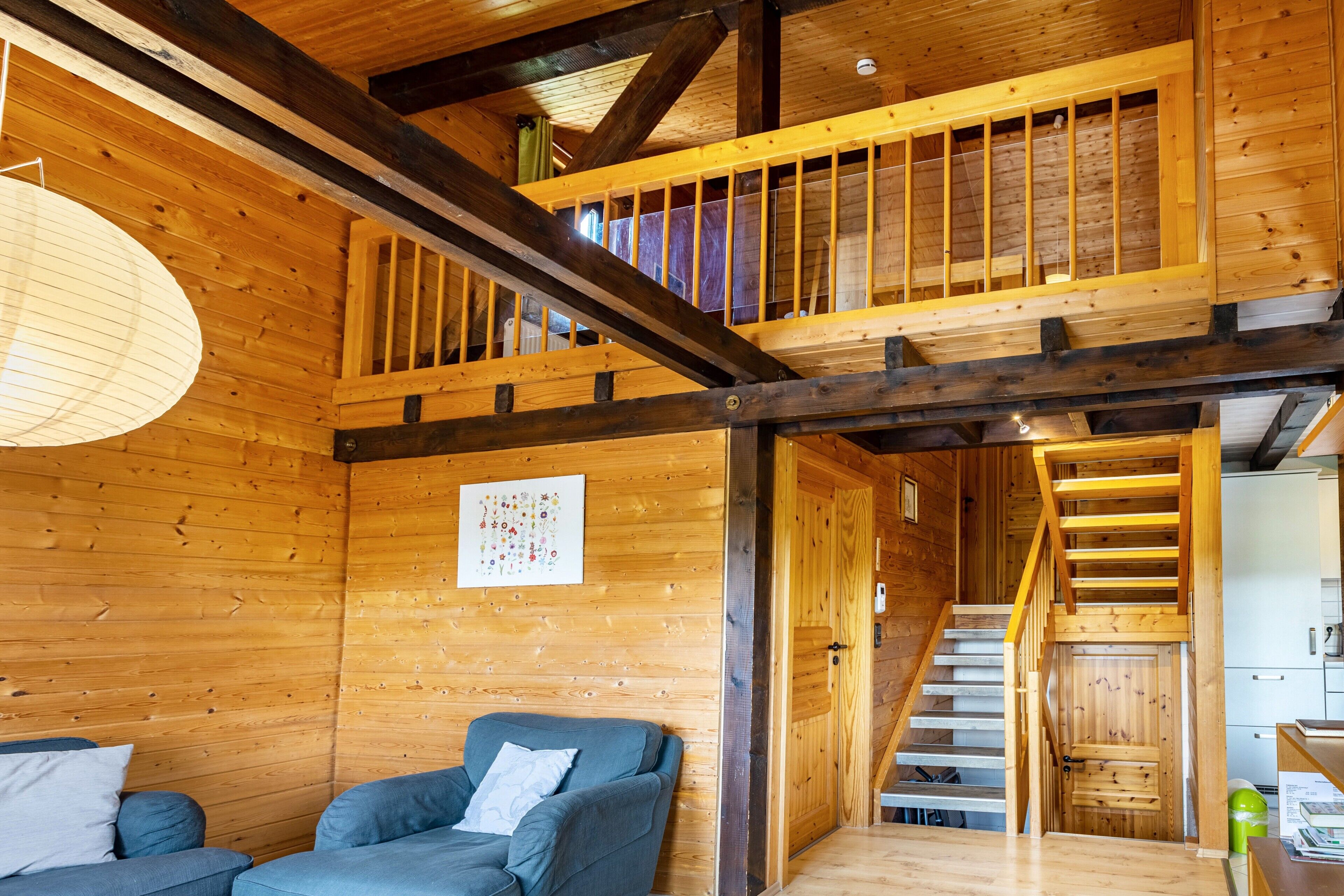 A wooden interior with a staircase, a sofa, and a wall-mounted light fixture.