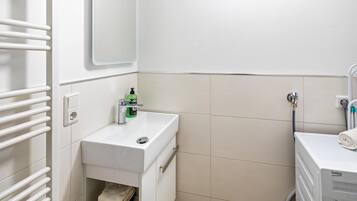 A bathroom with a white sink, a mirror, a towel rack, and a towel dispenser.