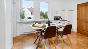 A modern kitchen with a dining table, chairs, a microwave, and a view of the outside. - Apartment "Goldberg" - Living in the Winery (Grünstadt)