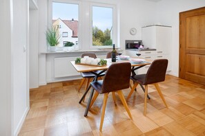 Une cuisine moderne avec une table à manger, des chaises, un four à micro-ondes et une vue sur l’extérieur.