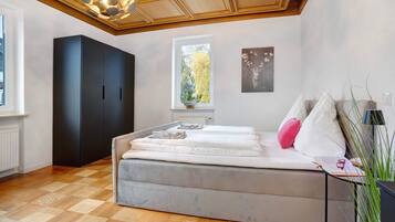 Een slaapkamer met een bed, een kledingkast, een raam met uitzicht en een plafondlamp.
