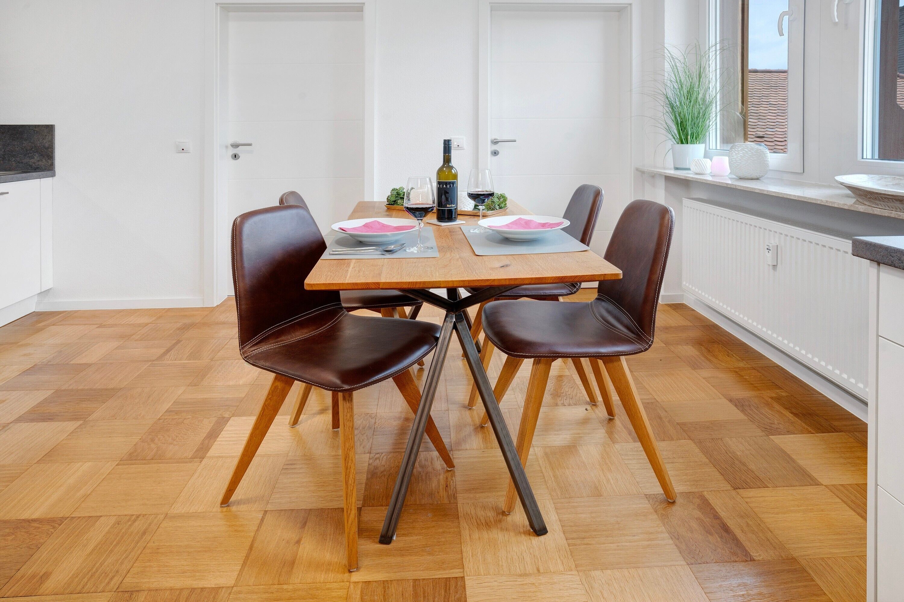 Un coin repas avec une table en bois, quatre chaises, une bouteille de vin et des verres.