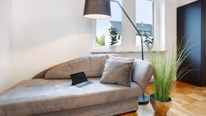 A modern living room with a sofa, a laptop, a floor lamp, and a potted plant. - Apartment "Goldberg" - Living in the Winery (Grünstadt)