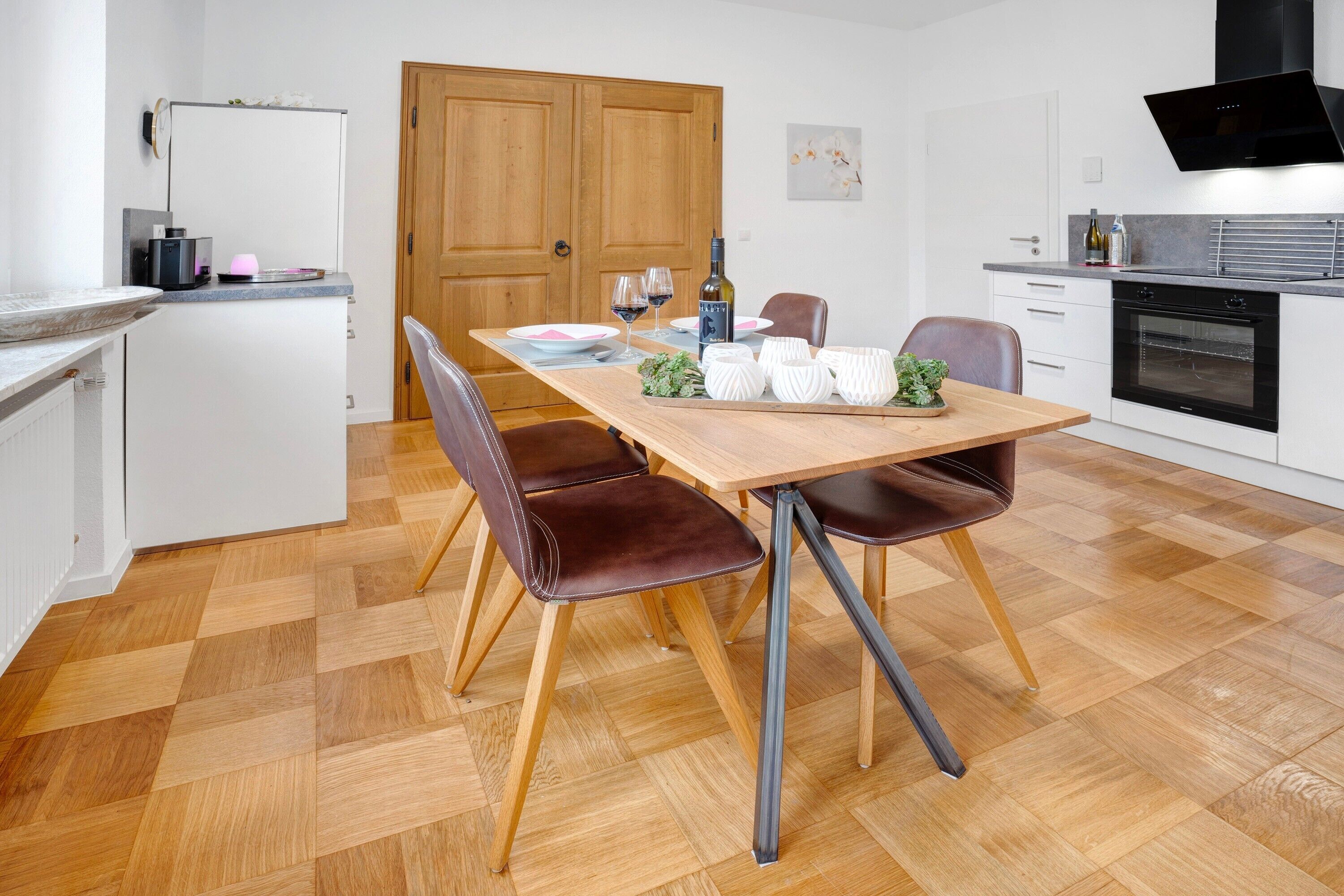 Eine moderne Küche mit Esstisch aus Holz, Stühlen und einem eingebauten Backofen.