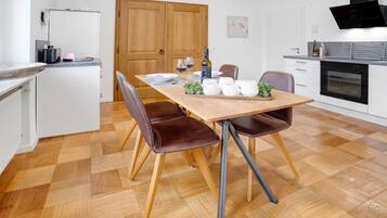 Eine moderne Küche mit Esstisch aus Holz, Stühlen und einem eingebauten Backofen.