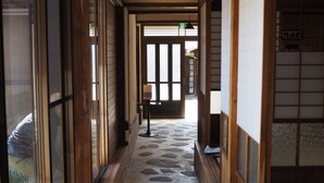 A traditional Japanese interior with a stone-tiled floor, wooden walls, and sliding doors. - okatei (Tonosho)