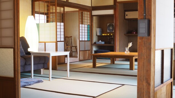 A traditional Japanese room with tatami flooring, a low table, a sofa, and a sliding door. - okatei (Tonosho)