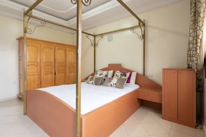 Ein Schlafzimmer mit Himmelbett, Holzschrank und einem kleinen Nachttisch.