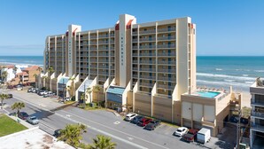 Un hôtel à plusieurs étages doté d’une piscine sur le toit, situé près d’une plage avec vue sur l’océan.
