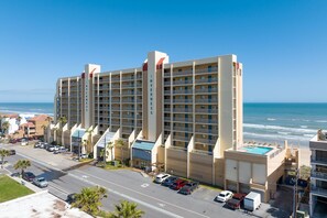 Un hôtel à plusieurs étages doté d’une piscine sur le toit, situé près d’une plage avec vue sur l’océan.
