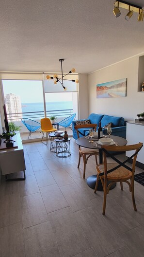 Enjoy the ocean view from the comfort of this living room, featuring a dining table, sofa, and coffee table.
