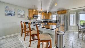Una cocina moderna con armarios de madera, electrodomésticos de acero inoxidable y una isla central con taburetes de bar.