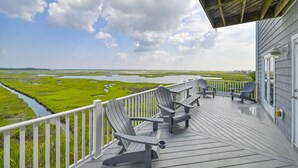 Una terraza con sillas Adirondack con vistas a un paisaje pantanoso.