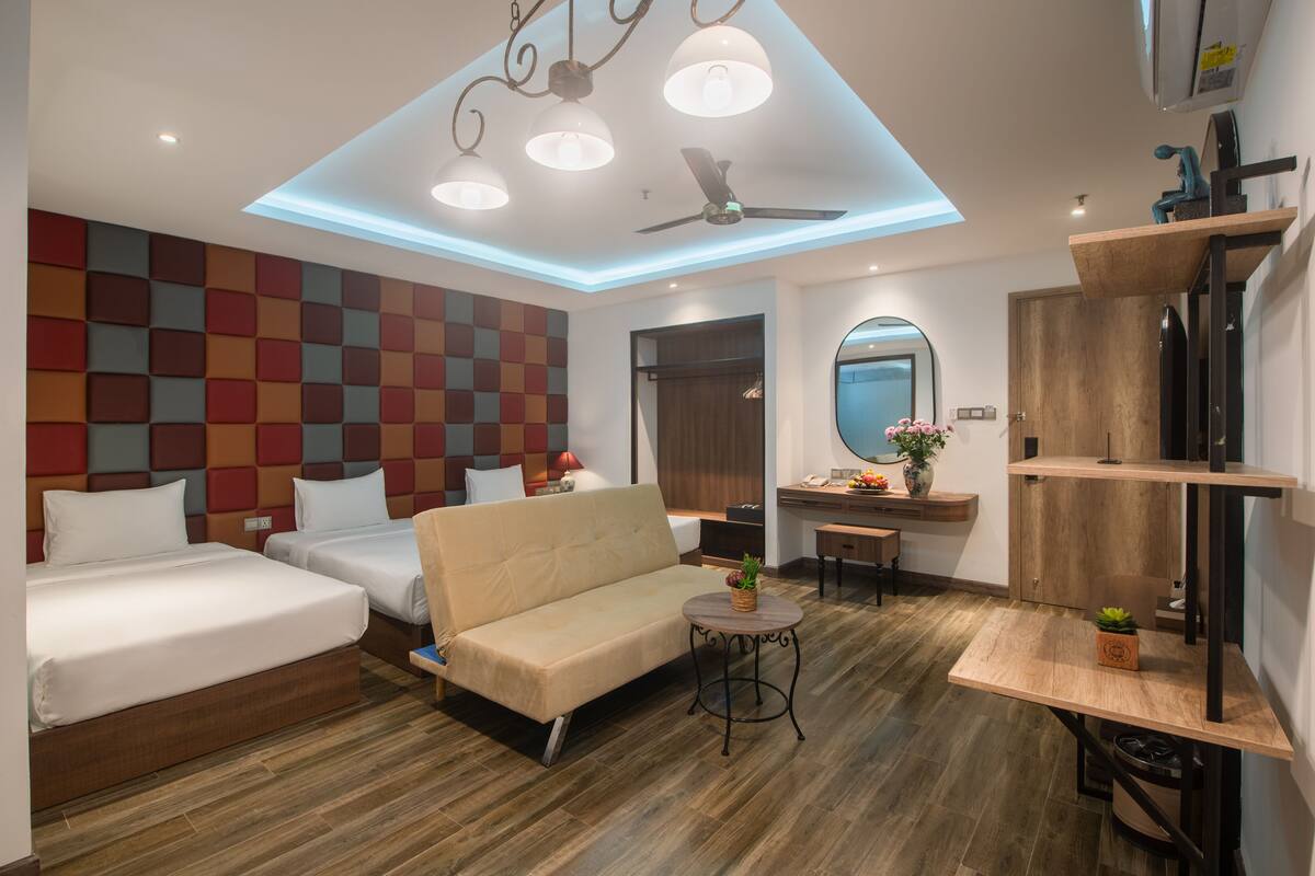 A modern hotel room with a bed, sofa, and a small dining table.